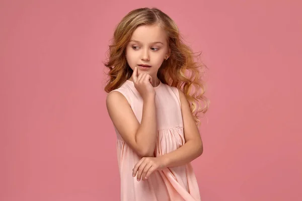 Petite fille aux cheveux bouclés blonds, dans une robe rose pose pour la caméra — Photo