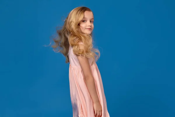 유행 소녀 핑크 드레스에 파란색 배경에 포즈. — 스톡 사진