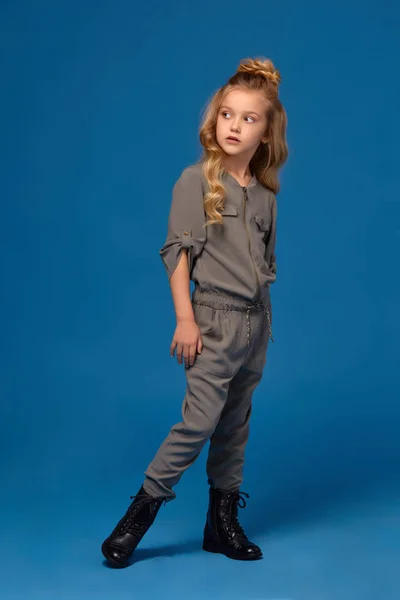 Маленькая девочка в модной одежде на синем фоне — стоковое фото