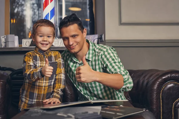 Jovem pai e seu filho na barbearia na sala de espera. — Fotografia de Stock