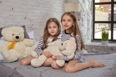İki küçük kız yatak odasında oturup resim.