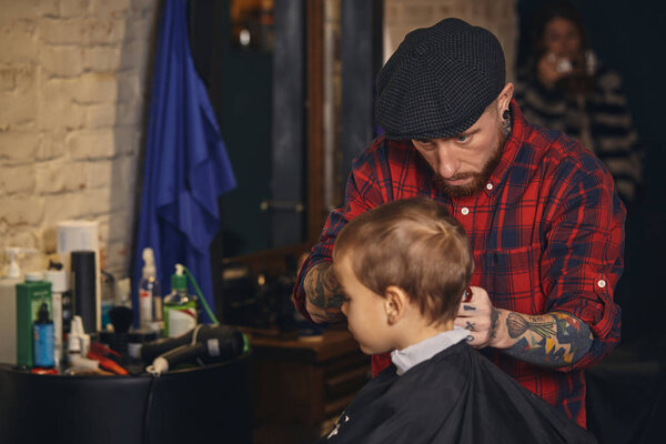 Caucasian boy getting haircut in barbershop indoor