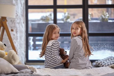 İki küçük kız yatak odasında oturup resim.