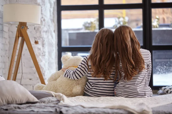 A imagem de duas irmãzinhas sentadas na cama no quarto . — Fotografia de Stock