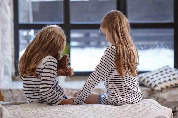 A imagem de duas irmãzinhas sentadas na cama no quarto . — Fotografia de Stock