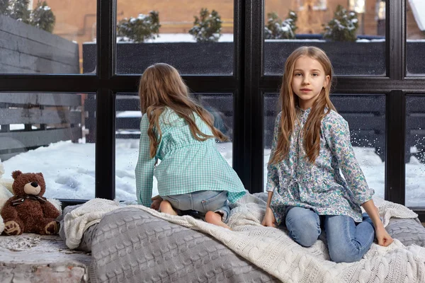 Obrázek dvou roztomilé sestřičky sedí na okenním parapetu — Stock fotografie