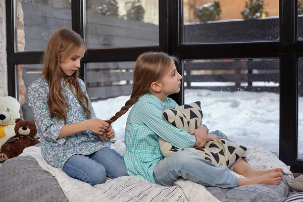 A képet, két aranyos kis nővér, ül az ablakpárkányon, a béke és a csend — Stock Fotó