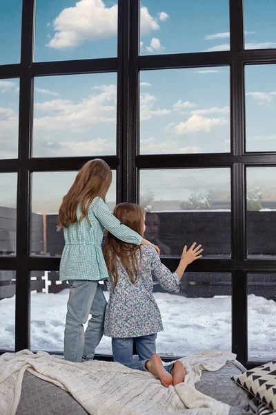 L'image de deux petites sœurs assises sur le rebord de la fenêtre, regardant la fenêtre — Photo