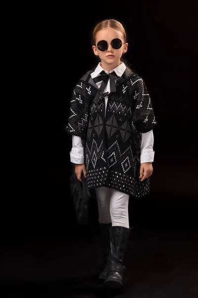 Маленькая девочка в черных очках, темное пончо, черные сапоги и сцепление в руке — стоковое фото