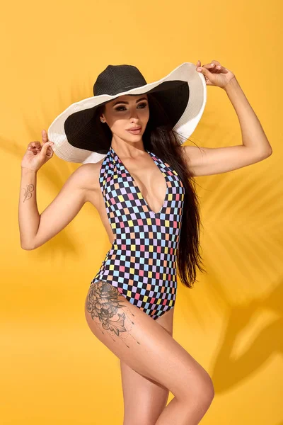 Joven morena sexy confiada posando delante de la cámara, usando bikini y gran sombrero negro agradable — Foto de Stock