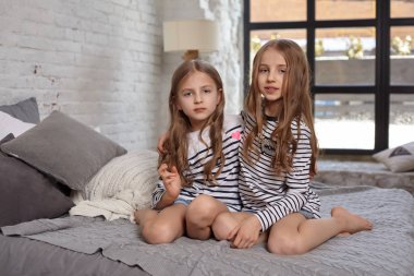 İki küçük kız yatak odasında oturup resim.