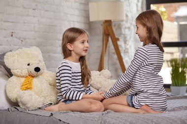 İki küçük kız yatak odasında oturup resim.