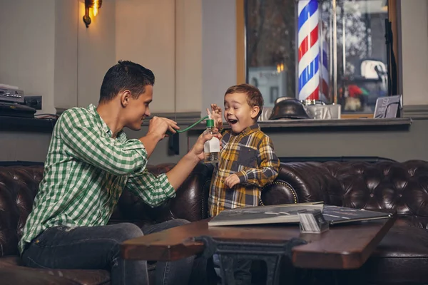 Jovem pai e seu filho na barbearia na sala de espera. — Fotografia de Stock