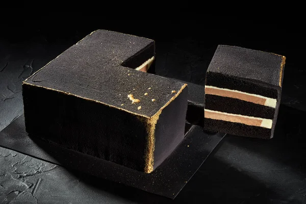 Torta quadrata nera con bordi in oro. Sfondo scuro. La vista dall'alto . — Foto Stock