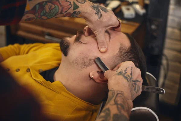 Клиент во время бритья бороды в парикмахерской — стоковое фото