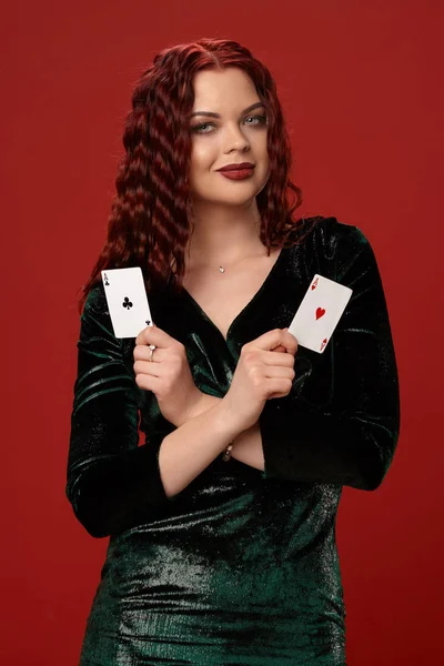 Giovane donna sexy con un rosso capelli ricci tenendo assi, su uno sfondo rosso. Poker — Foto Stock