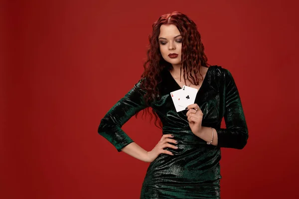 Fiatal szexi nő, egy vörös göndör haja gazdaság ász, piros háttéren. Póker — Stock Fotó