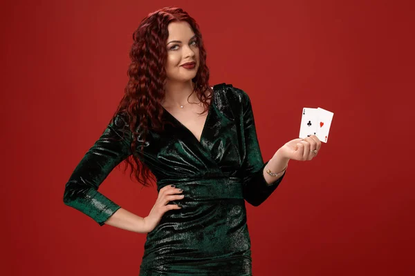 Mladá sexy žena s červenými kudrnatými vlasy drží ESA, na červeném pozadí. Poker — Stock fotografie