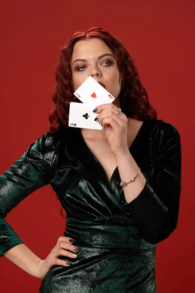 Mujer sexy joven con un pelo rizado rojo sosteniendo ases, sobre un fondo rojo. Poker — Foto de Stock