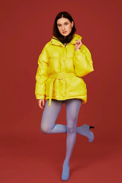 Retrato de estudio de una joven morena con chaqueta amarilla y pantalón azul gris mangueras o medias. Captura de estudio — Foto de Stock