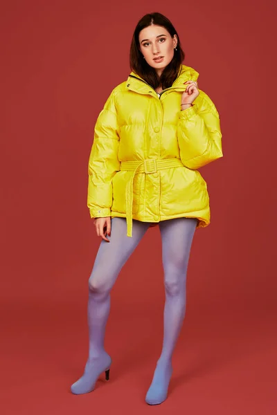 Retrato de estudio de una joven morena con chaqueta amarilla y pantalón azul gris mangueras o medias. Captura de estudio — Foto de Stock