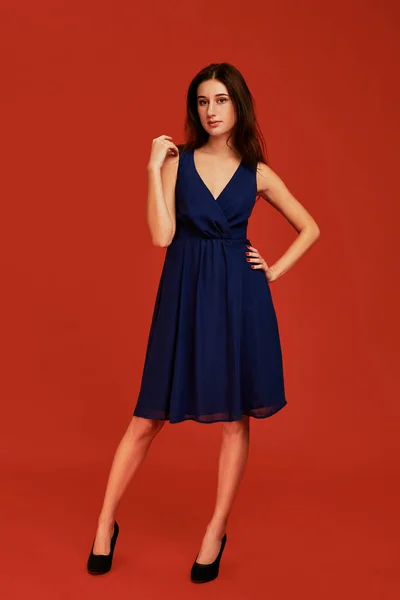 Красивая молодая брюнетка в элегантном голубом коктейльном платье и на высоких каблуках позирует перед камерой — стоковое фото