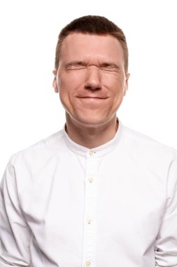 Beyaz gömlekli yakışıklı genç çekici yüzler, beyaz bir arka plan üzerinde izole dururken yapıyor