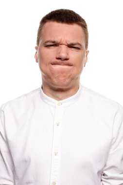 Beyaz gömlekli yakışıklı genç çekici yüzler, beyaz bir arka plan üzerinde izole dururken yapıyor