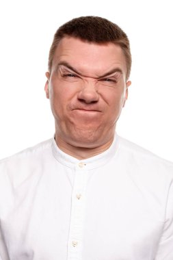 Beyaz gömlekli yakışıklı genç çekici yüzler, beyaz bir arka plan üzerinde izole dururken yapıyor