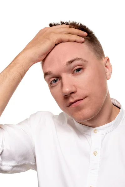 Encantador joven guapo con una camisa blanca está haciendo caras, mientras está de pie aislado sobre un fondo blanco —  Fotos de Stock