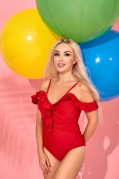 Genç seksi ince kadın bir kırmızı mayo onun elinde balonlarla bir stüdyoda poz. — Stok fotoğraf