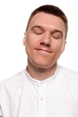 Beyaz gömlekli yakışıklı genç çekici yüzler, beyaz bir arka plan üzerinde izole dururken yapıyor