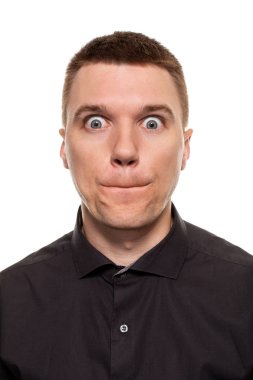 Yakışıklı genç bir siyah gömlekli yüzler, beyaz bir arka plan üzerinde izole dururken yapıyor