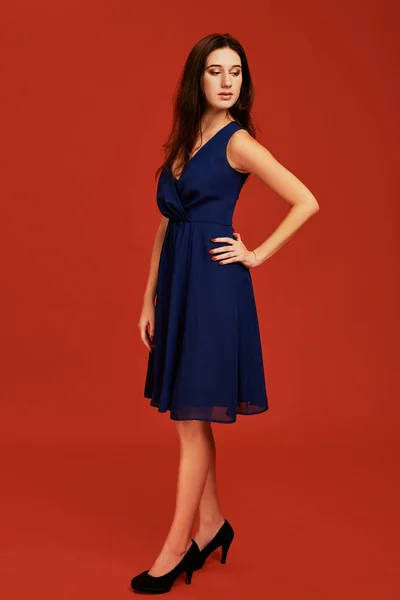 Красивая молодая брюнетка в элегантном голубом коктейльном платье и на высоких каблуках позирует перед камерой — стоковое фото