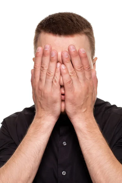 Knappe jonge man in een zwart shirt is het maken van gezichten, terwijl staande geïsoleerd op een witte achtergrond — Stockfoto