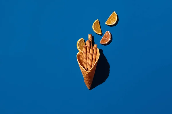 Waffelrollen und Marmelade aus Waffelkegel auf blauem Hintergrund — Stockfoto