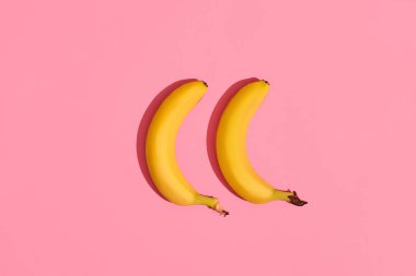 Bir çift pembe bir arka plan görüntüsünün, üstten görünüm merkezinde yanında yalan muz bileşimi