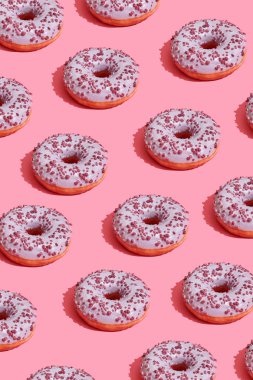 Mercan pembe pastel arka plan üstten görünüm desen lezzetli pembe sırlı çörek ile gıda tasarım