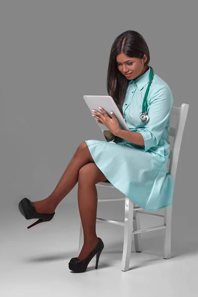 Młode ładne lekarz z stetoskop siedzi na krześle — Zdjęcie stockowe