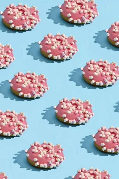 Food design with tasty pink glazed donut on blue pastel background top view pattern
