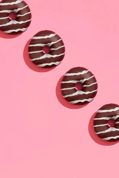 Diseño de alimentos con sabroso donut glaseado de chocolate con tiras blancas en coral rosa pastel fondo superior ver patrón — Foto de Stock