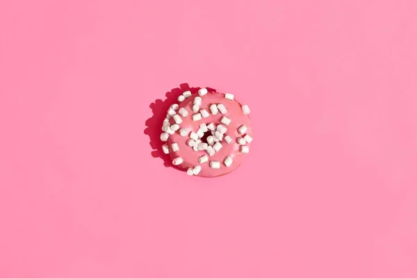 Food design. Close up high quality image of pink glazed donut on coral pink background