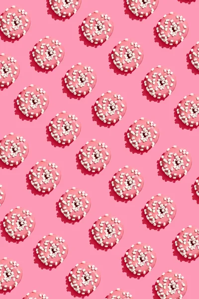 Diseño de alimentos con sabroso rosado esmaltado donut en coral rosa pastel fondo superior ver patrón —  Fotos de Stock