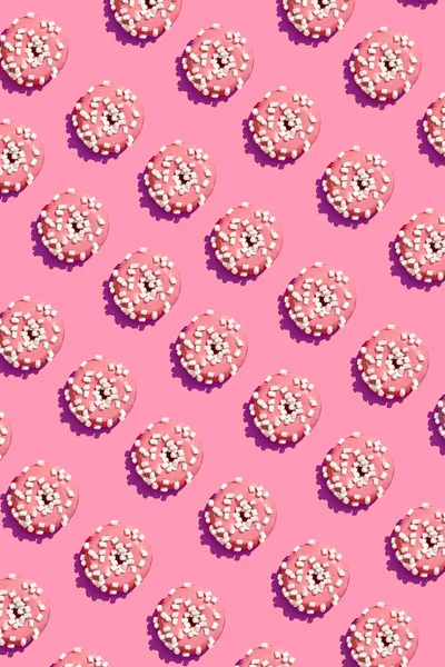 Дизайн їжі зі смачно-рожевим глазурованим пончиком на кораловому рожевому пастельному фоні зверху візерунок — стокове фото