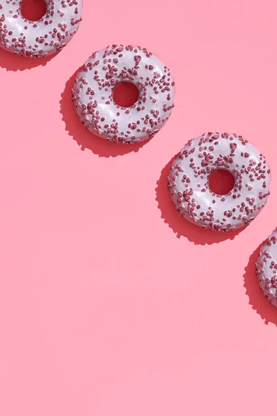 Diseño de alimentos con sabroso rosado esmaltado donut en coral rosa pastel fondo superior ver patrón — Foto de Stock