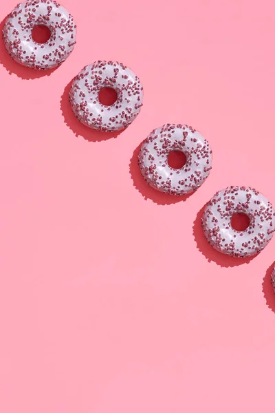 Diseño de alimentos con sabroso rosado esmaltado donut en coral rosa pastel fondo superior ver patrón — Foto de Stock