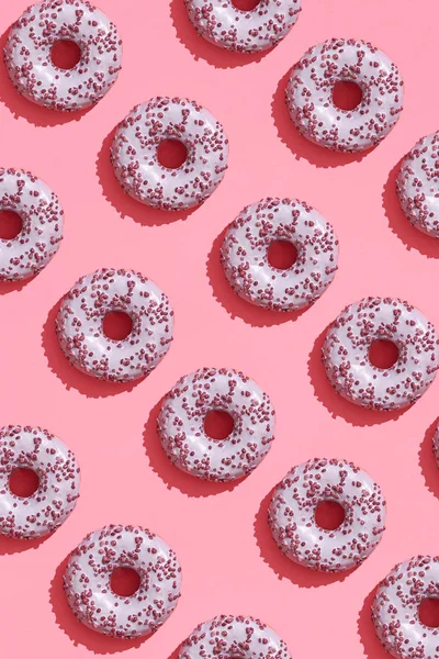 Diseño de alimentos con sabroso rosado esmaltado donut en coral rosa pastel fondo superior ver patrón — Foto de Stock