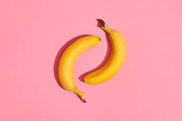 Composizione di un paio di banane che si trovano accanto a uno sfondo rosa al centro dell'immagine, vista dall'alto — Foto Stock