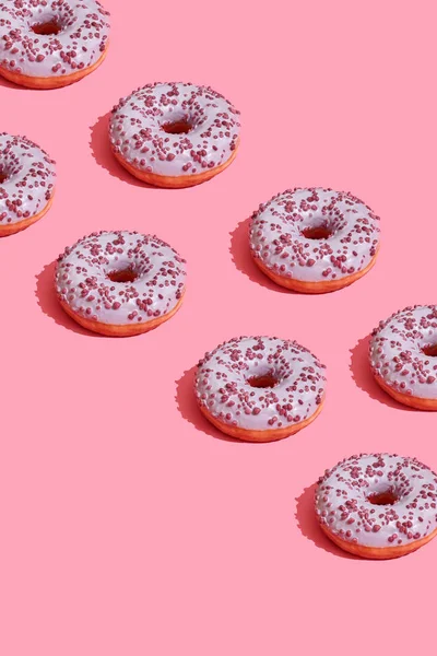 Matdesign med läckra rosa glaserade donut på korall rosa pastell bakgrundsmönster ovanifrån — Stockfoto