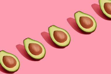 Renkli meyve desen mercan pembe arka plan, üstten görünüm üzerinde çukurları ile taze kesilerek avokado yarıya indirir